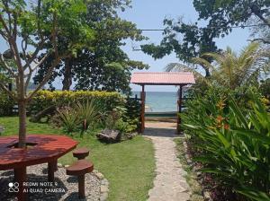 a garden with a bench and the ocean in the background at CocoMar Hostal in Acanti +4 photos