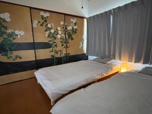 a bedroom with two beds and a painting of flowers at ゲストハウス樹 in Shingū
