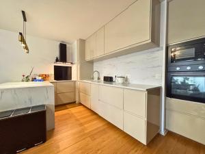 a kitchen with white cabinets and a sink and a microwave at Bezons Golden - 3 chambres - 3min du Tramway #SirDest in Bezons