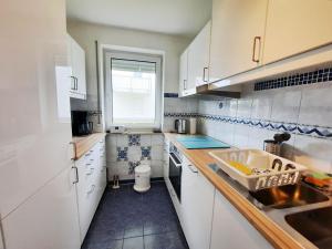 a kitchen with white cabinets and a sink and a window at Haus Heidelbeere 22 in Graal-Müritz