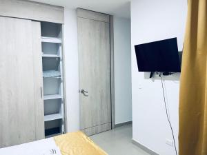 a bedroom with a closet with a tv and a door at Aparta Hotel Nini Cali in Cali