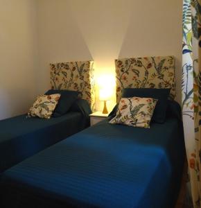 1 dormitorio con 2 camas con sábanas azules y lámpara en Villa bellevue, en Fanjeaux
