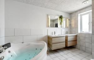 a white bathroom with a tub and two sinks at 8 Bedroom Nice Home In Rømø in Bolilmark +20 photos