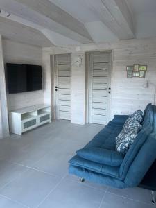 a living room with a blue couch and a flat screen tv at Holiday Home Kenese in Balatonkenese