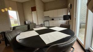 a room with a table and chairs and a kitchen at Bungalow Noordzee B in Julianadorp +3 photos