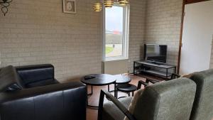 a living room with a couch and a table and a tv at Bungalow Noordzee B in Julianadorp