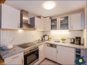 Una cocina con gabinetes blancos y encimera. en Villa Ernst Whg 08, en Ahlbeck 5 fotos más