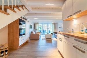 Una cocina con gabinetes blancos y una sala de estar. en Haus am Siel 01, zentral mit eigenem Steg, en Greetsiel