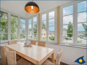 a dining room with a table and chairs and windows at Villa Ernst Whg 09 in Ahlbeck