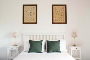 a bedroom with a white bed with green pillows at Il Giardino di Elena in Montiano