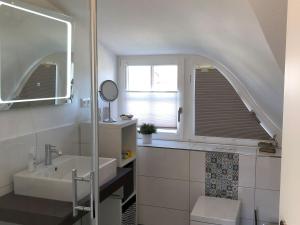 a white bathroom with a sink and a window at Reethaus "dat huus" in Zierow +4 photos