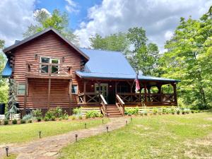 a log cabin with a porch and a flag at Mossy Falls Cabin by Leavetown Vacations in Altamont