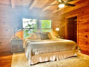 a bedroom with a bed with a ceiling fan and a window at Mossy Falls Cabin by Leavetown Vacations in Altamont