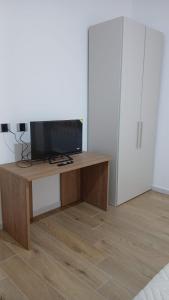 a room with a desk with a tv and a refrigerator at Riccabea in Alghero