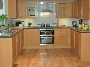 une cuisine avec des armoires en bois et un four à plaques de cuisson dans l'établissement Home Park Farm Cottages A, à Lanteglos