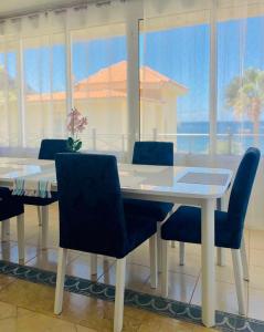 a dining room with a white table and blue chairs at Villa Sol Los Cristianos in Los Cristianos