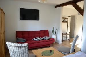 a living room with a red couch and a table at Neue moderne Ferienwohnung, separater Eingang, Seenähe in Möllen +7 photos