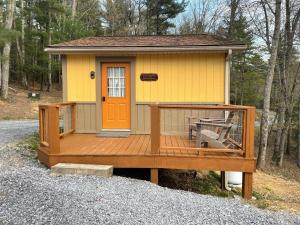 une petite maison jaune avec une terrasse en bois dans l'établissement The Country Cottage by On Cue Properties, à Ghent
