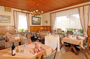 una sala da pranzo con tavoli, sedie e lampadario a braccio di Landgasthaus Zum Naturschutzpark a Bispingen