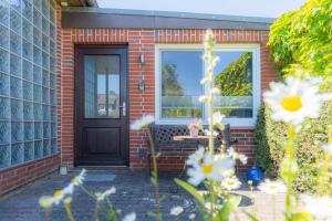 a brick house with a black door and flowers at Wohnung Mien Kajuet ID 455 in Oldenswort