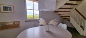 a white dining room with a white table and stairs at Reethaus "53 Nord" in Zierow