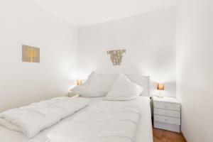Dormitorio blanco con cama con sábanas blancas y mesita de noche en Grömitz-Center Whg 209, en Grömitz