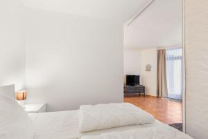 Un dormitorio blanco con una cama y un espejo. en Grömitz-Center Whg 209, en Grömitz 12 fotos más