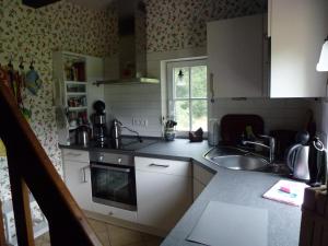 a kitchen with white cabinets and a sink at Bickbeerhütte in Westerstede +33 photos