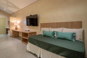 une chambre avec un lit avec des oreillers bleus et une télévision dans l'établissement Recanto Alvorada Eco Resort, à Brotas