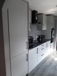 a kitchen with white cabinets and black counter tops at Newly renovated & furnished luxury bedroom in Kirkliston
