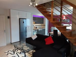 een woonkamer met een zwarte bank en een keuken bij Le centre historique au calme in Dinan