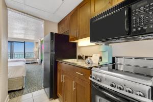 eine Küche mit Herd und ein Bett in einem Zimmer in der Unterkunft Pink Surf by StayMareni - Oceanfront 2 Queens Suite in Myrtle Beach