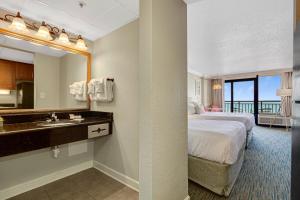 ein Hotelzimmer mit einem Bett und einem Bad mit einem Waschbecken in der Unterkunft Pink Surf by StayMareni - Oceanfront 2 Queens Suite in Myrtle Beach + 25 Fotos