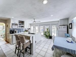 una cucina con mobili bianchi, tavolo e sedie di The White House by Leavetown Vacations a Wrightsville