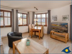 a living room with a table and a tv at Villa Ricarda Whg 03 in Ahlbeck