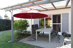 Un patio con una mesa y una sombrilla roja. en Ferienhaus Ahorn, en Göhren-Lebbin