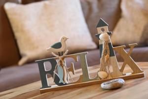 Un cartel de madera sobre una mesa con conchas y una casa. en Ferienhaus Ahorn, en Göhren-Lebbin