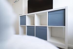 a white shelf with blue drawers on a wall at Solymar Whg 64 in Grömitz +15 photos