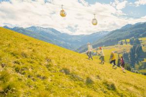 a group of people walking up a hill near a ski lift at Hotel Glemmtalerhof in Saalbach-Hinterglemm