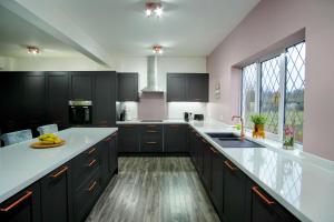 eine Küche mit schwarzen Schränken und weißen Arbeitsplatten in der Unterkunft Northfield Cottage, Games & Arcade Room, Dog Friendly HS2, NEC, BHX, M42, Family Gatherings, Contractors, Hot Tube Hire Optional in Hampton in Arden