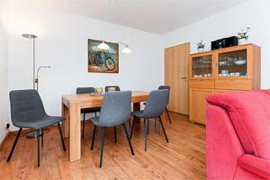 a dining room table with chairs and a pink couch at Ferienhaus Möwenweg in Neuharlingersiel