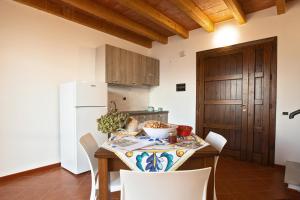 a kitchen with a table with chairs and a white refrigerator at Casa Arconides in Motta D'affermo