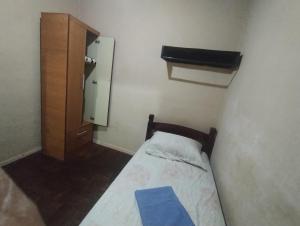 a small bedroom with a bed and a cabinet at Quartos individuais na saída do metrô estação Glória in Rio de Janeiro