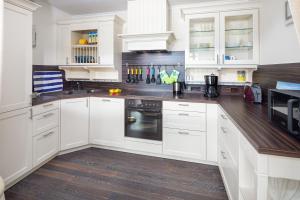 a white kitchen with white cabinets and black appliances at Haus Nordseeblick Whg 141 in Norderney