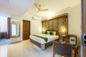 a bedroom with a bed and a chair in a room at Treebo Trend Akshaya Lalbagh Inn in Bangalore