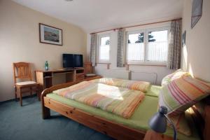 ein Schlafzimmer mit einem Bett und einem Schreibtisch und zwei Fenstern in der Unterkunft Restaurant-Pension Bürgerhof in Bad Zwesten