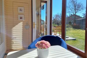 eine Vase mit Blumen auf einem Tisch auf einer Veranda in der Unterkunft Deelswai 50, Bungalow in Goting + 3 Fotos