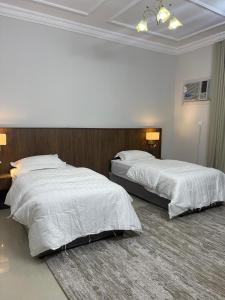 two beds in a hotel room with white sheets at شقة ثلاثة غرف نوم وصالة 1 in Al Baha