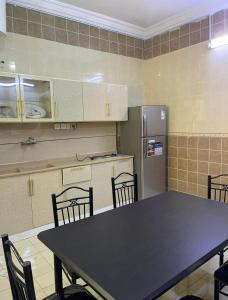 a kitchen with a table and chairs and a refrigerator at شقة ثلاثة غرف نوم وصالة in Al Baha +4 photos