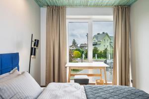ein Schlafzimmer mit einem Bett und einem Tisch und einem Fenster in der Unterkunft Mano Malibu in Melnragė